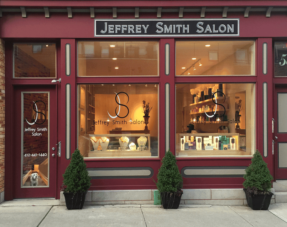 Salon storefront with large windows and stylish interior near the entrance.